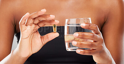 Buy stock photo Hand, woman and supplement pill in studio with glass water for health, omega 3 and results of medical wellness. Person, pharma tablet and magnesium for essential oil, vitamins on grey background