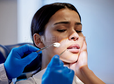 Buy stock photo Shot of a young woman experiencing pain and anxiety while having a dental procedure performed on her