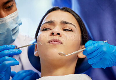 Buy stock photo Shot of a young woman experiencing anxiety while having a dental procedure performed on her