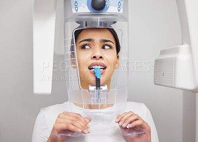 Buy stock photo Shot of a young woman looking anxious while using an x ray machine at a dentist’s office