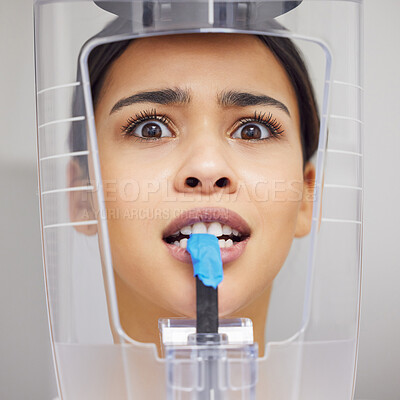 Buy stock photo Shot of a young woman looking anxious while using an x ray machine at a dentist’s office