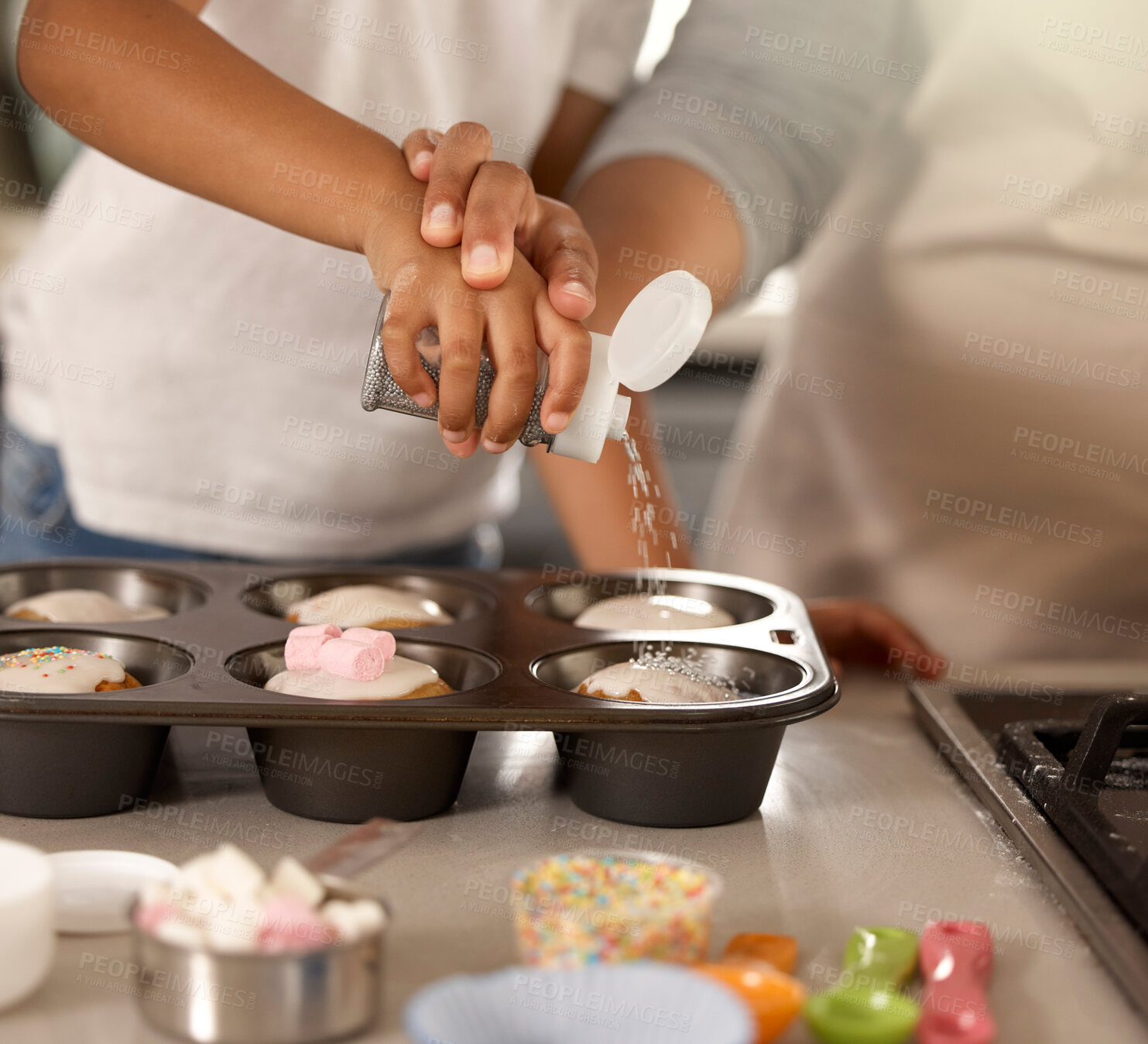 Buy stock photo Cropped shot of an unrecognizable little girl baking cupcakes with her mom at home