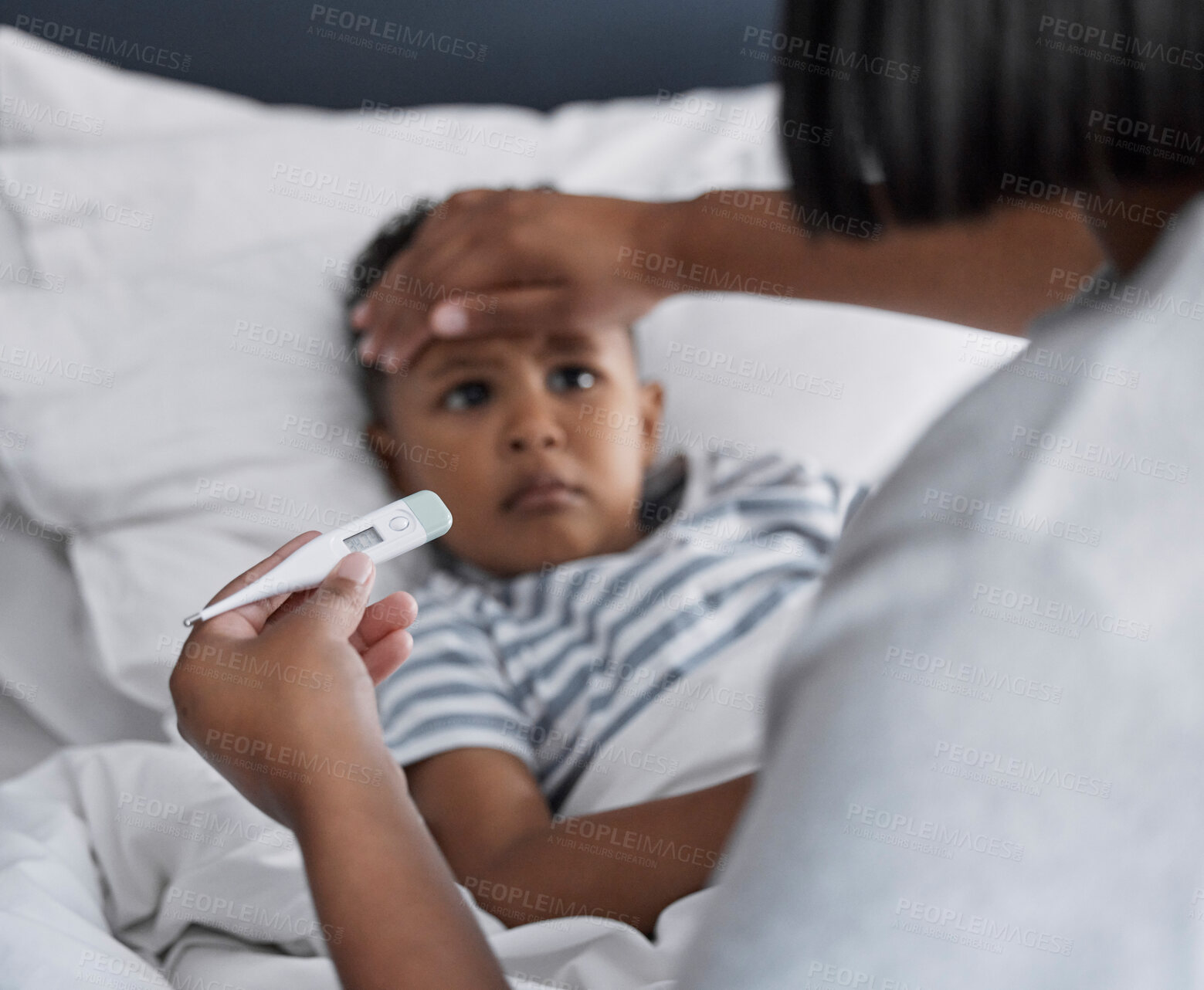 Buy stock photo Shot of a little boy lying in bed and feeling sick while his mother checks his temperature