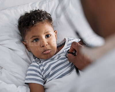 Buy stock photo Shot of an adorable little boy lying in bed and feeling sick while a paediatrician uses a stethoscope