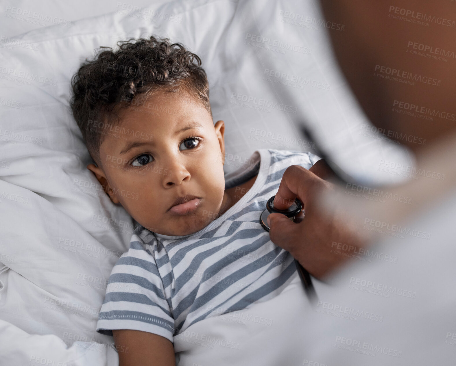 Buy stock photo Shot of an adorable little boy lying in bed and feeling sick while a paediatrician uses a stethoscope