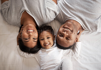 Buy stock photo High angle shot of a young couple lying in bed and bonding with their son at home