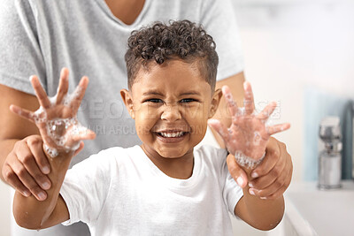 Buy stock photo Shot of an adorable little boy standing in the bathroom and washing his hands while his mother helps him