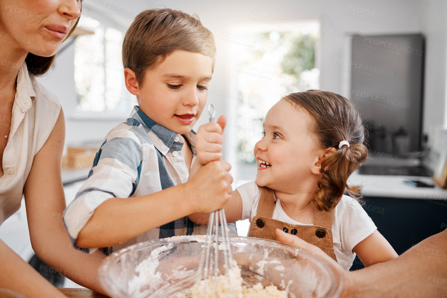 Buy stock photo Shot of two siblings baking together at home with the help of their mother