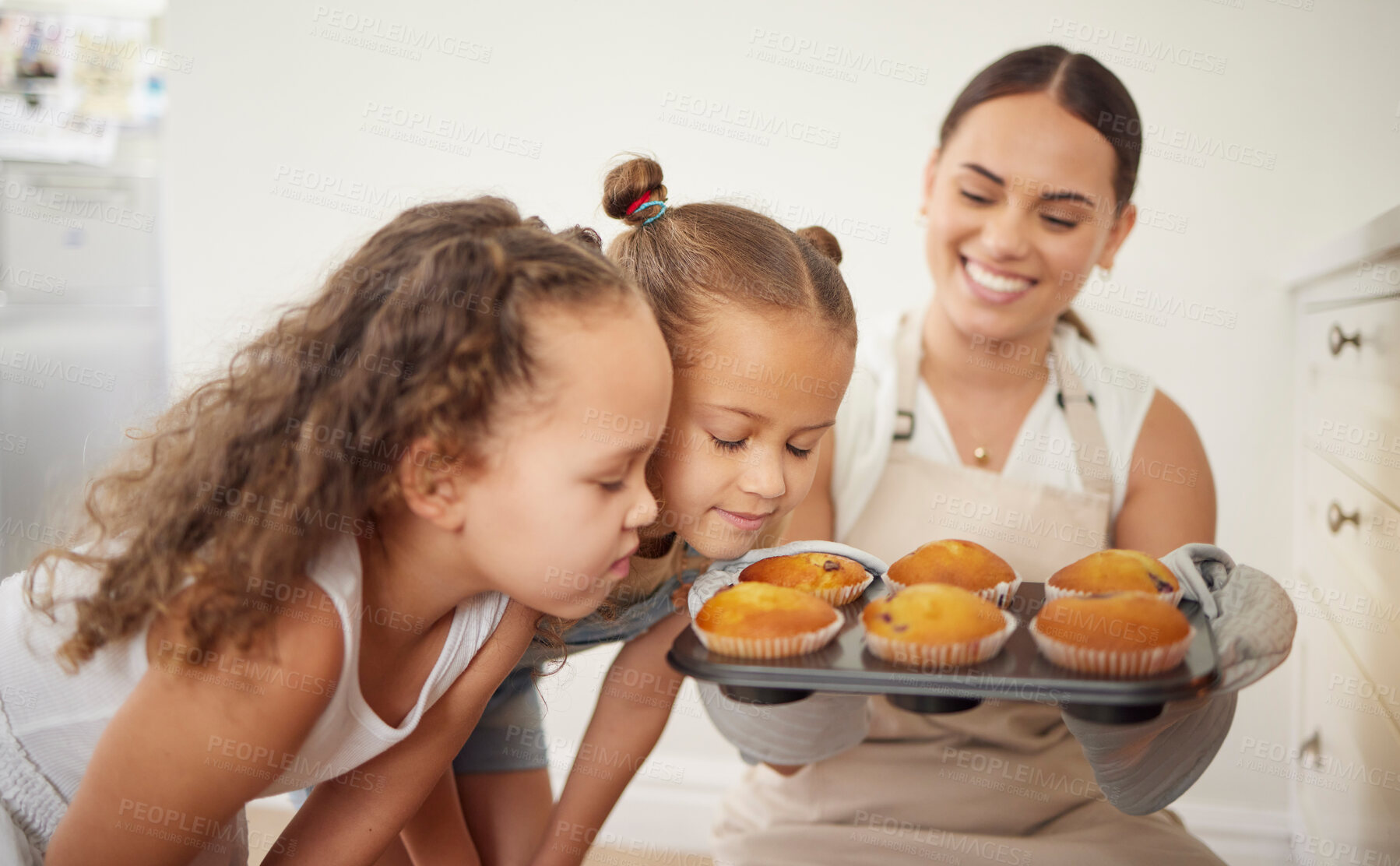 Buy stock photo Shot of a young mother and her daughter smelling the muffins they baked at home