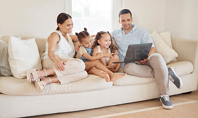 Buy stock photo Shot of a young family looking at something on a laptop while sitting at home