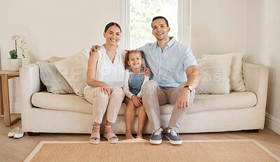 Buy stock photo Shot of a young couple sitting at home with their daughter