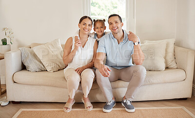 Buy stock photo Shot of a young couple sitting at home with their adorable daughter