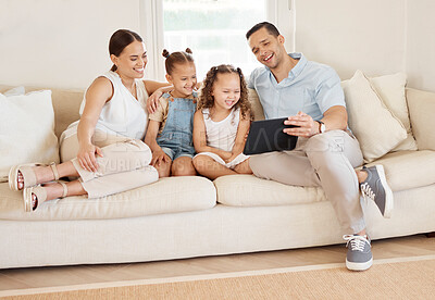Buy stock photo Shot of a young family sitting together while looking at something on a digital tablet