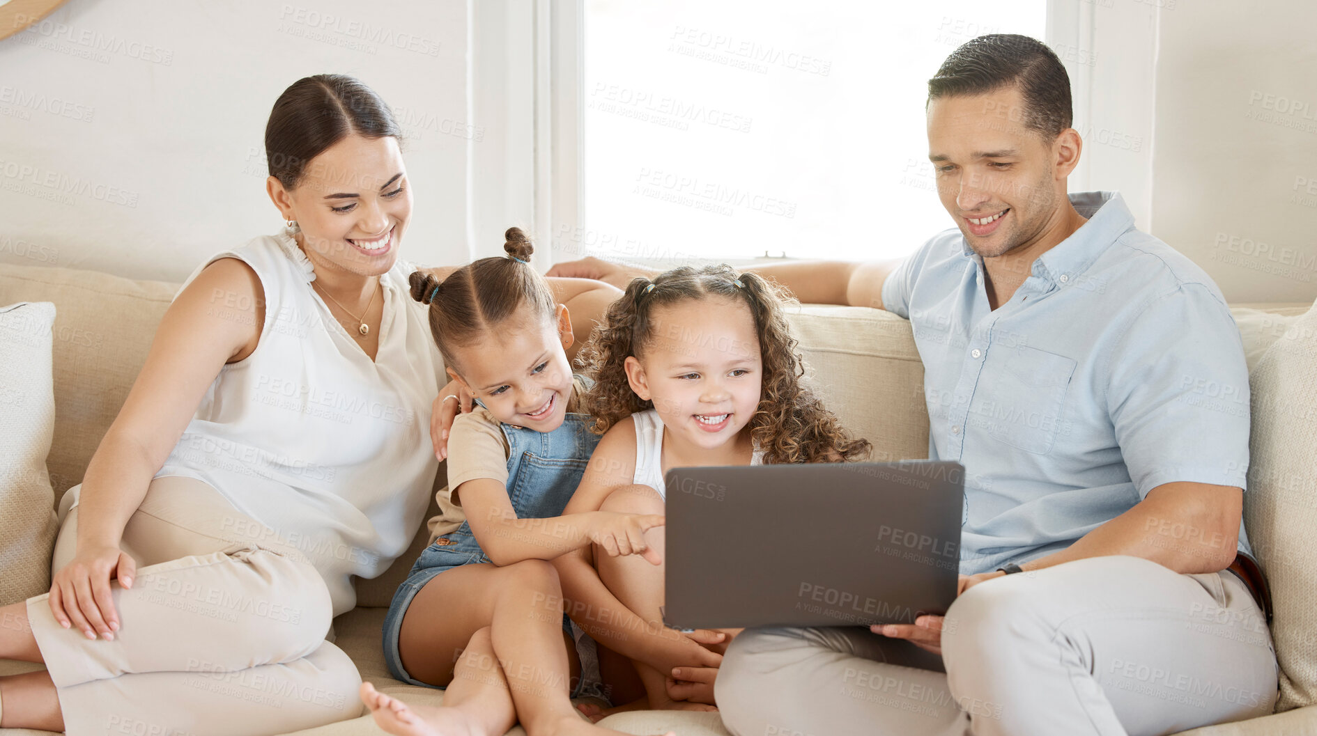 Buy stock photo Shot of a young family looking at something on a laptop while sitting at home