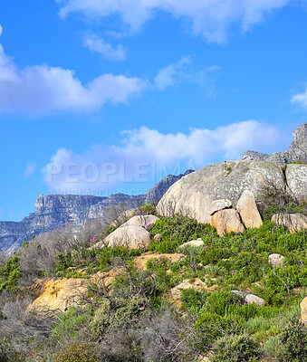 Buy stock photo Beautiful, quiet and calm view of a mountain with green plants growing in a rocky area. Peaceful landscape of a mountainside against a cloudy blue background on a summer day in nature