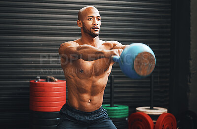 Buy stock photo Shot of a muscular young man exercising with a kettlebell in a gym