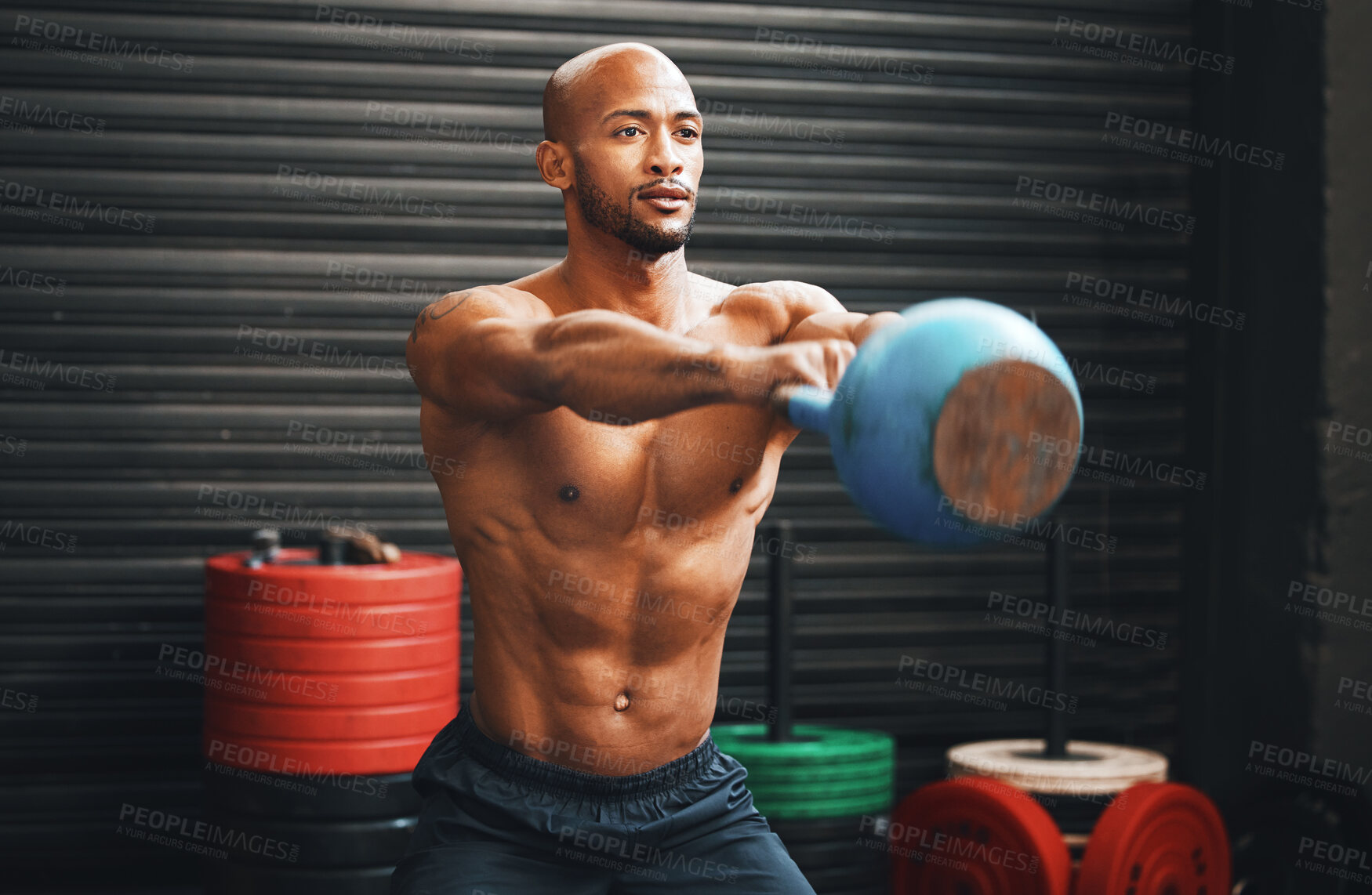 Buy stock photo Shot of a muscular young man exercising with a kettlebell in a gym