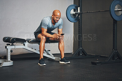 Buy stock photo Fitness, phone and happy man relax in gym to check health progress, exercise results or wellness update. Sport, mobile app or bodybuilder on break for online schedule, workout tutorial or typing text