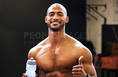 Buy stock photo Portrait of a muscular young man showing thumbs up while drinking water in a gym