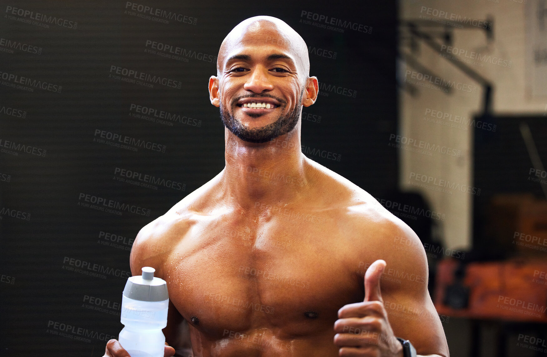 Buy stock photo Portrait of a muscular young man showing thumbs up while drinking water in a gym