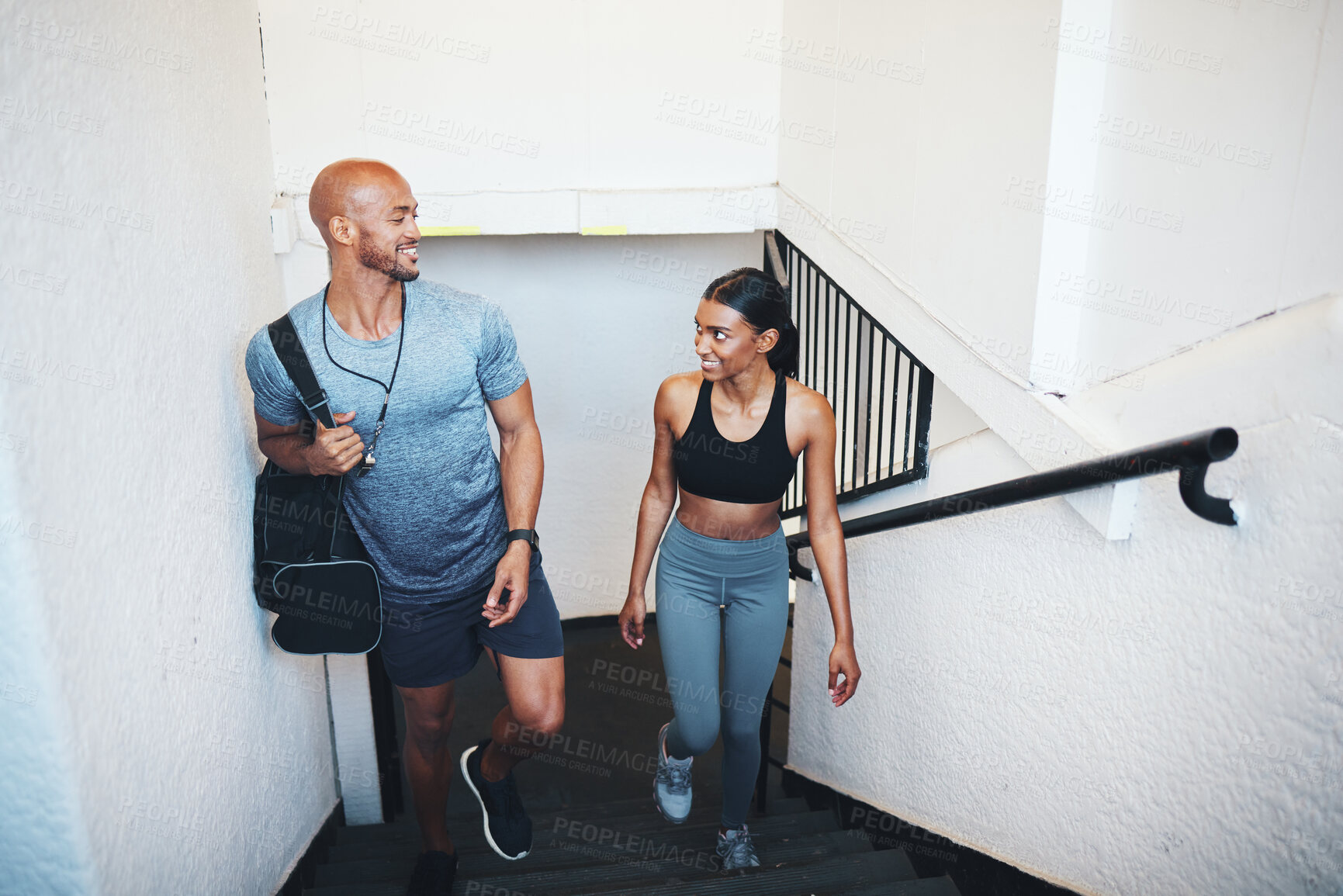 Buy stock photo Shot of a sporty young man and woman walking up a staircase together