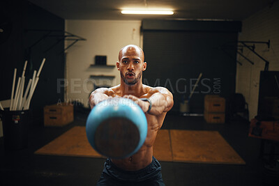 Buy stock photo Shot of a muscular young man exercising with a kettlebell in a gym