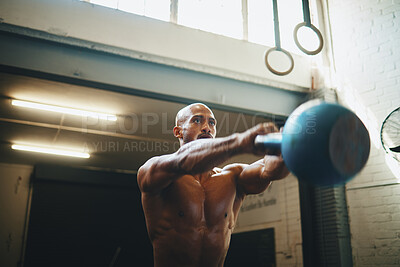 Buy stock photo Low angle shot of a muscular young man exercising with a kettlebell in a gym