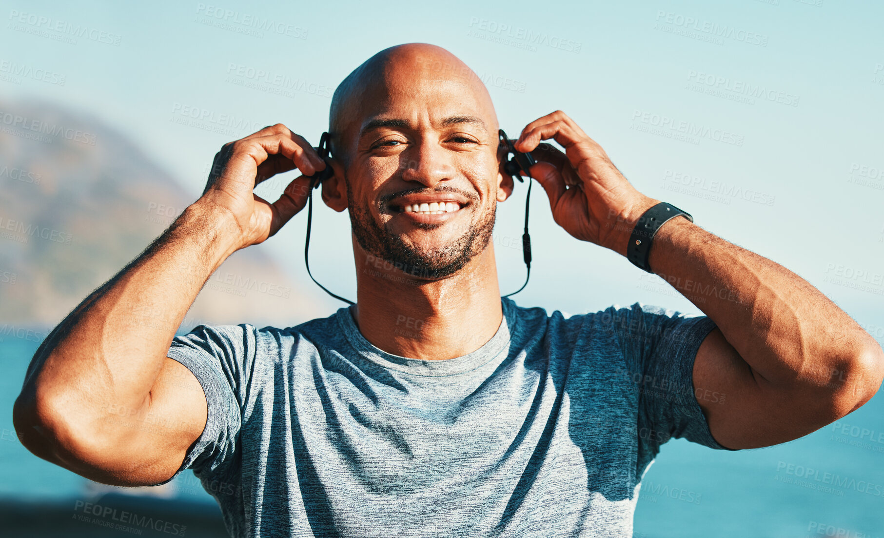 Buy stock photo Shot of a sporty young man wearing earphones while out for a workout