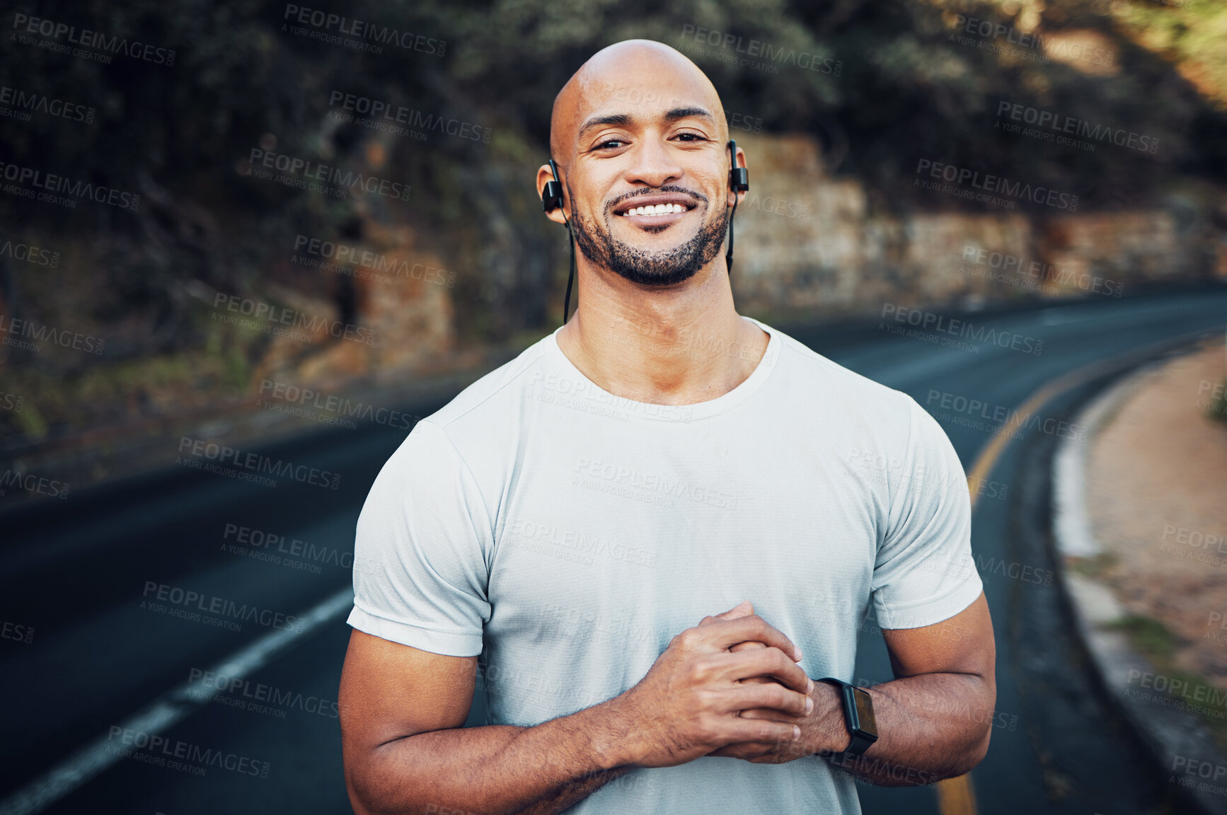 Buy stock photo Shot of a sporty young man wearing earphones while out for a workout