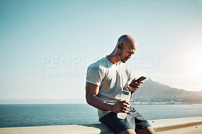 Buy stock photo Shot of a young man sitting and using his phone outside