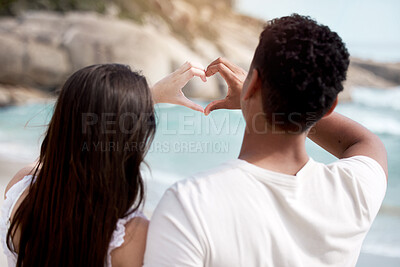 Buy stock photo Couple, beach and love with heart hands for valentines day, support or care together in nature. Rear view of man and woman with emoji for review, feedback or outdoor romance by sea or ocean coast