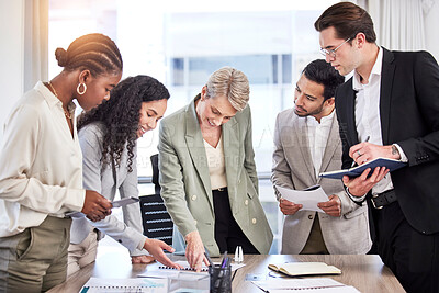 Buy stock photo Shot of a diverse group of businesspeople using technology and looking at paperwork during a meeting in the office