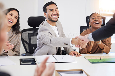 Buy stock photo Shot of a handsome young businessman sitting and shaking hands with his colleagues during a meeting