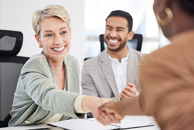 Buy stock photo Shot of a mature businesswoman sitting and shaking hands with her colleagues during a meeting in the office