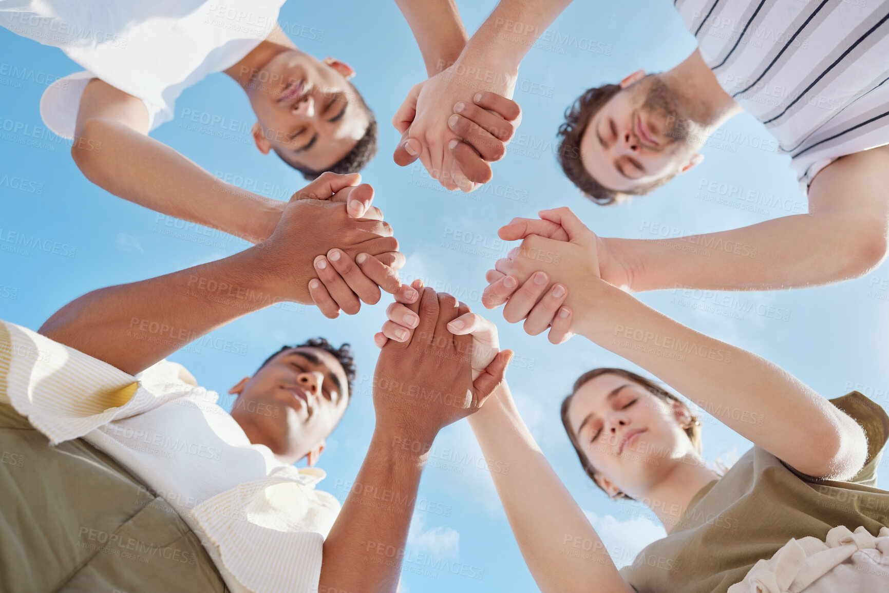 Buy stock photo Shot of a group of young people holding hands while praying outside