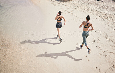 Buy stock photo High angle shot of two unrecognizable athletic young women out for a run on the beach
