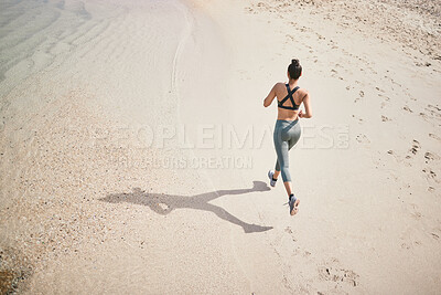 Buy stock photo High angle shot of an unrecognizable athletic young woman out for a run on the beach