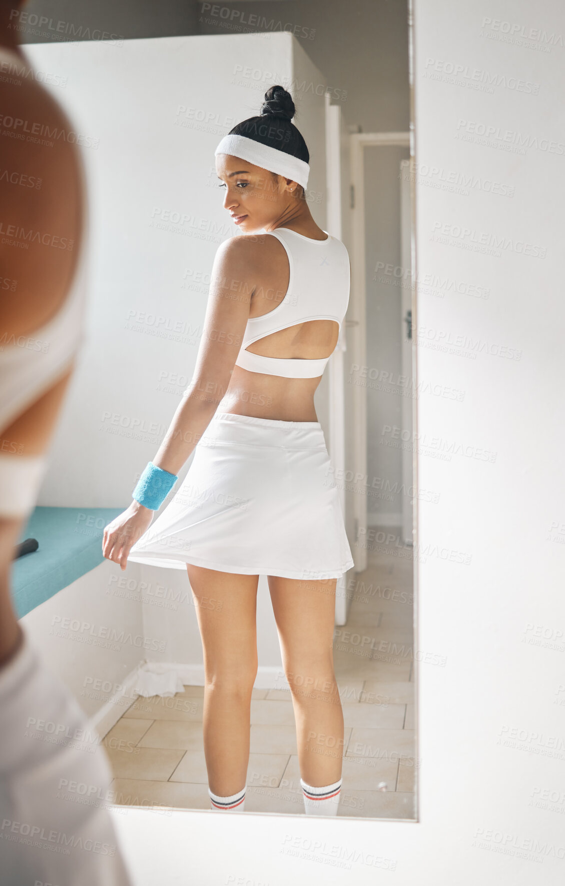 Buy stock photo Shot of an attractive young woman checking herself in the mirror in the locker room at a tennis arena