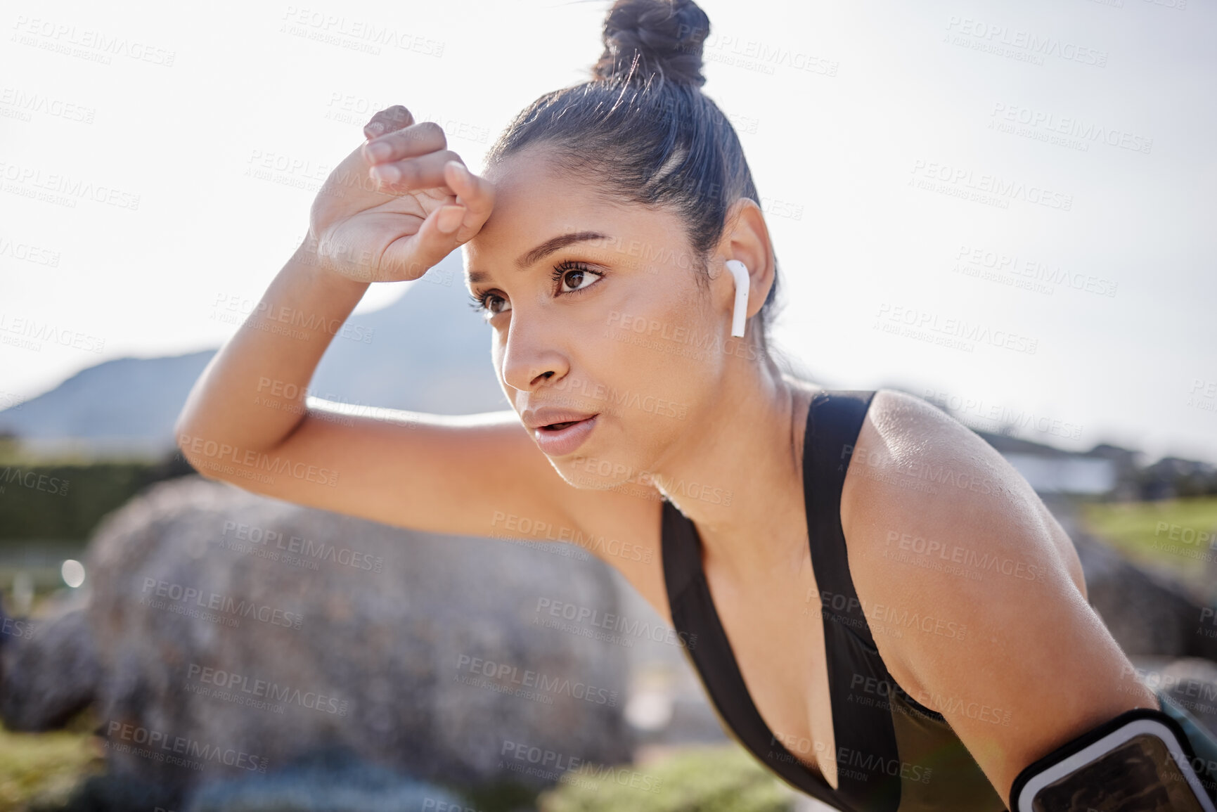 Buy stock photo Shot of a young woman taking a break after going for a run outdoors