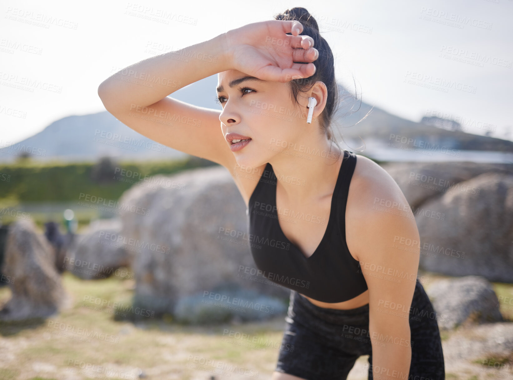 Buy stock photo Shot of a young woman taking a break after going for a run outdoors