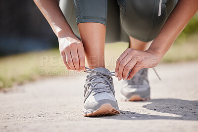 Buy stock photo Shot of an unrecognisable woman tying her shoelaces before going for a run outdoors