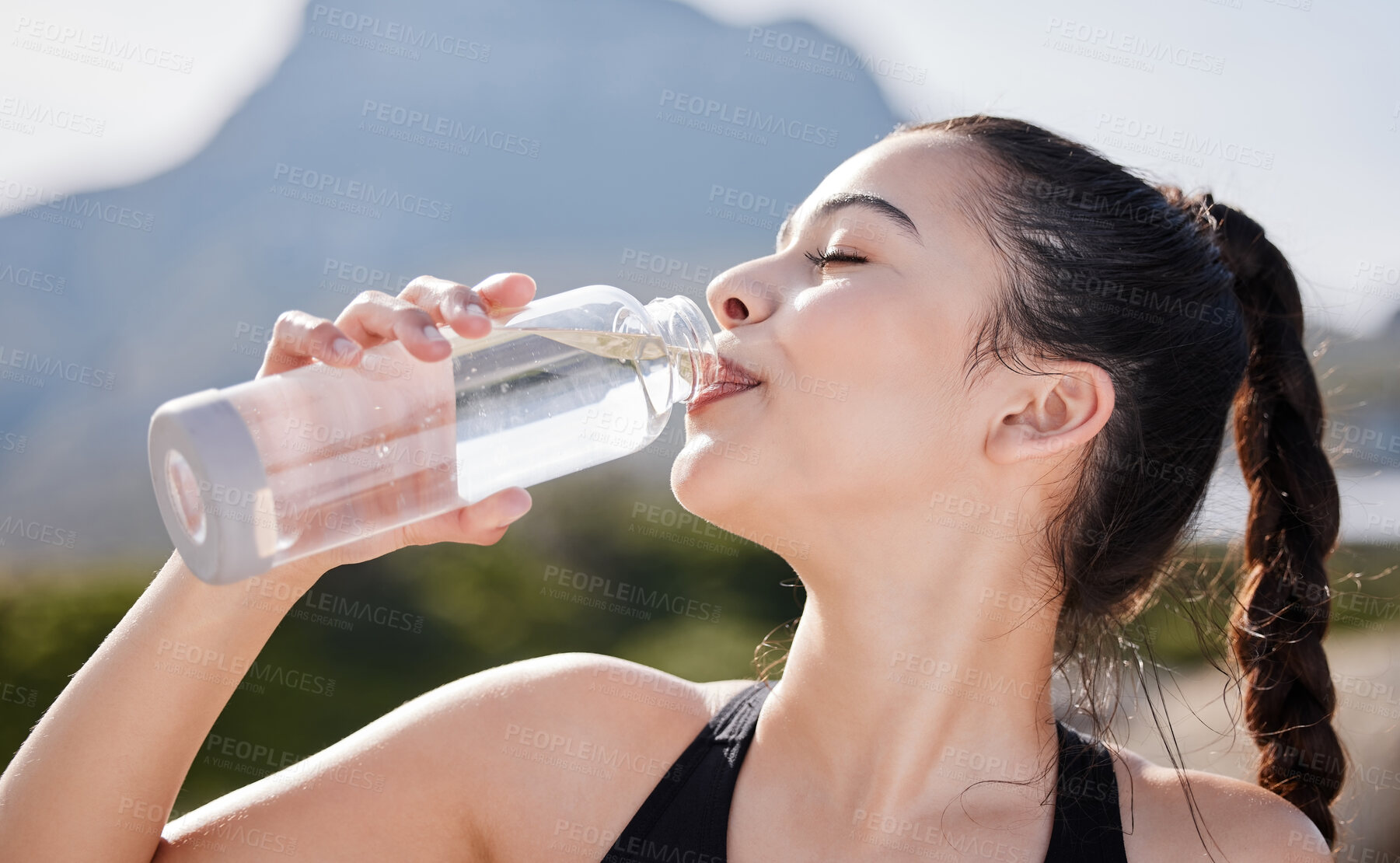 Buy stock photo Shot of a young woman drinking water after working out in nature