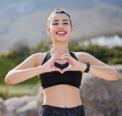 Buy stock photo Portrait of a fit young woman making a heart shaped gesture after going for a run outdoors