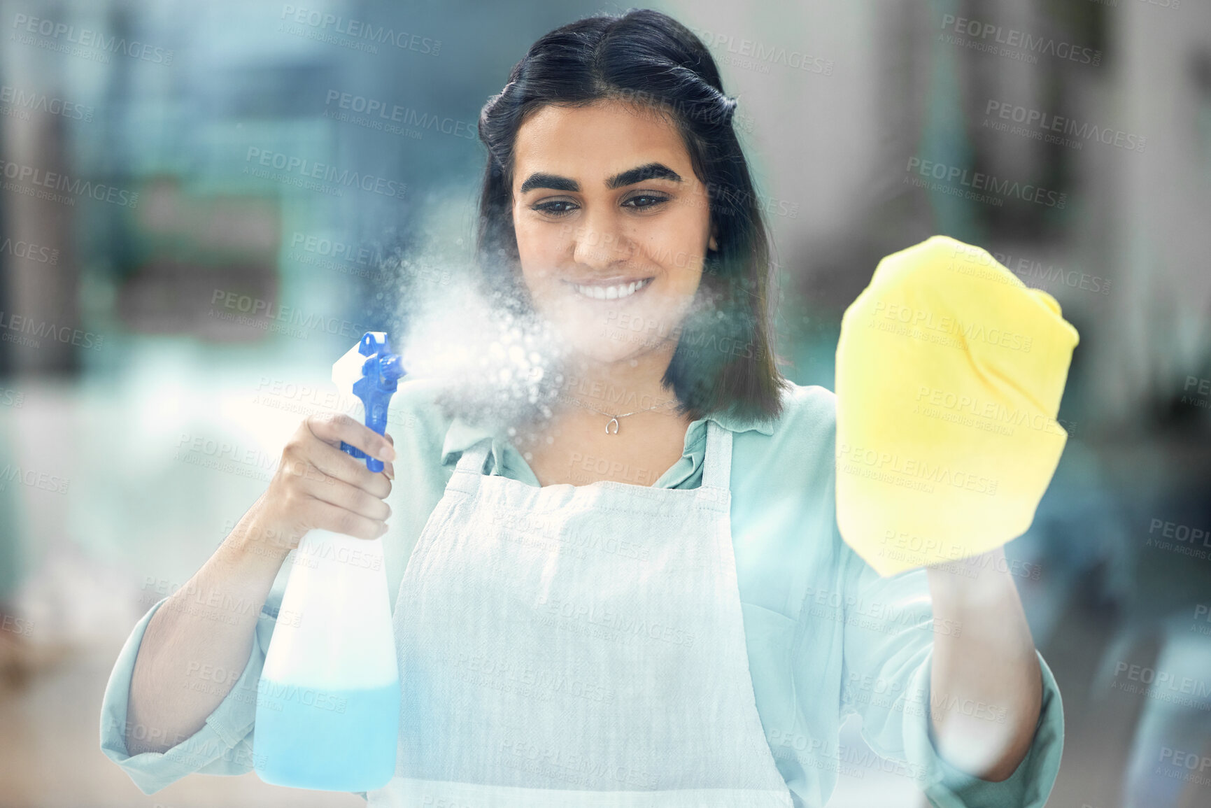 Buy stock photo Woman, spray and smile with gloves on cloth in house for cleaning, scrub and dirt on window. Housekeeper, happy and apron with textile or detergent in bottle for dust in home by living room.