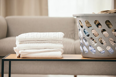 Buy stock photo Clean laundry, table and basket in home living room for folding, hospitality and housekeeping. Towel stack, plastic bucket and spring cleaning service for fabric, clothes and hygiene on desk in house