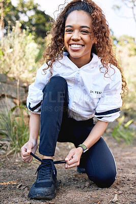 Buy stock photo Shot of a beautiful young woman tying her shoes before a run