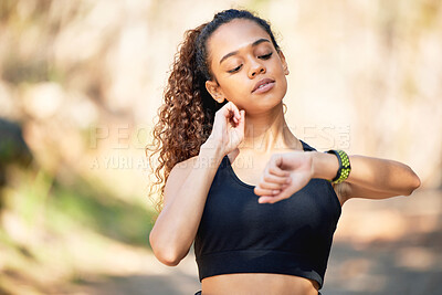 Buy stock photo Shot of a young woman checking her smart watch and taking her pulse