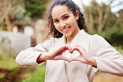 Buy stock photo Portrait of an attractive young female university student making a heart shape with her hands while standing outside on campus
