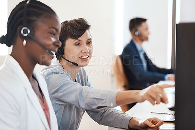 Buy stock photo Shot of two call centre agents working together on a computer in an office