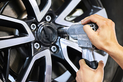 Buy stock photo Cropped shot of an unrecognizable male mechanic fixing a tyre at his workshop during a car service